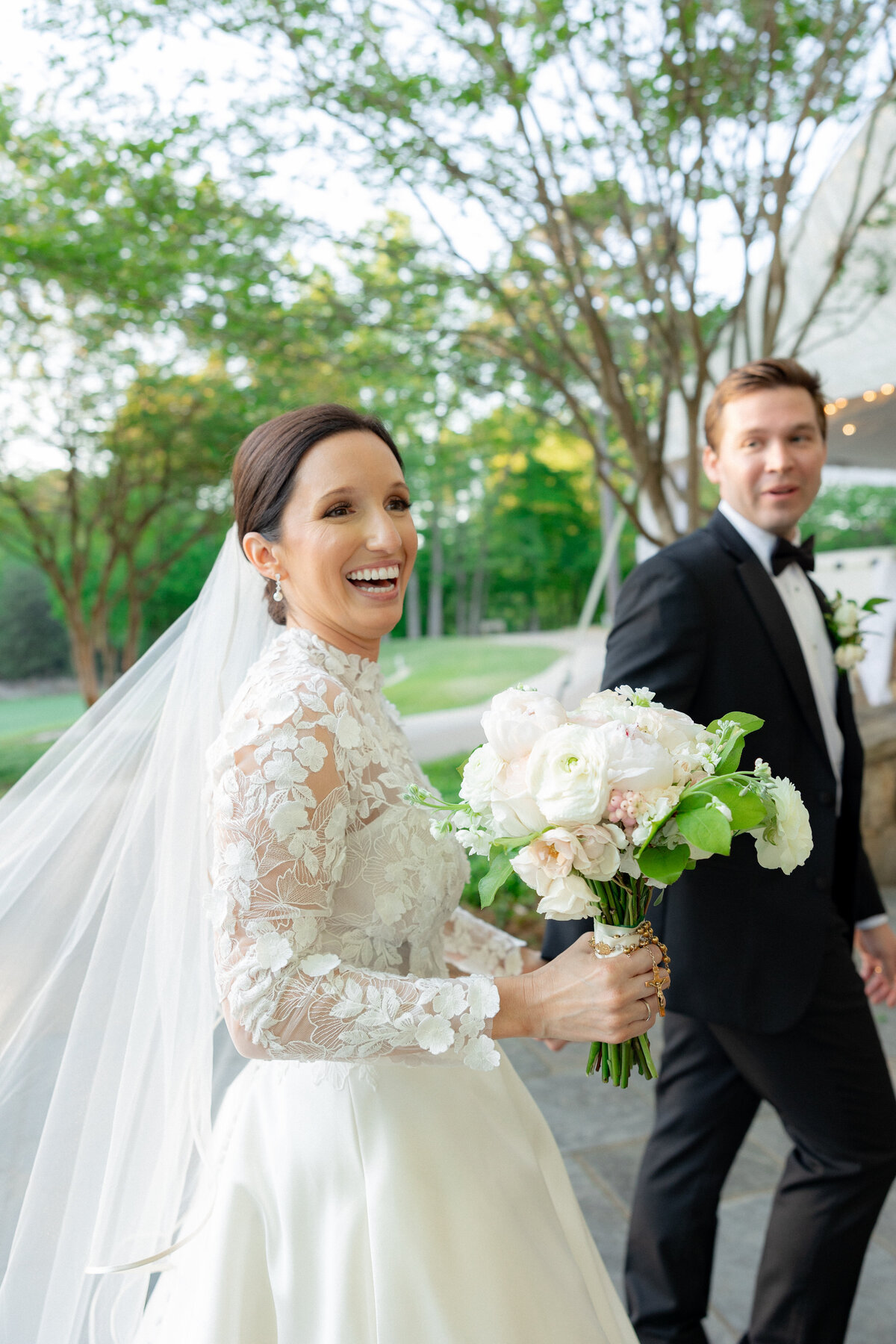 Dark haired bride holding hands with groom while smiling