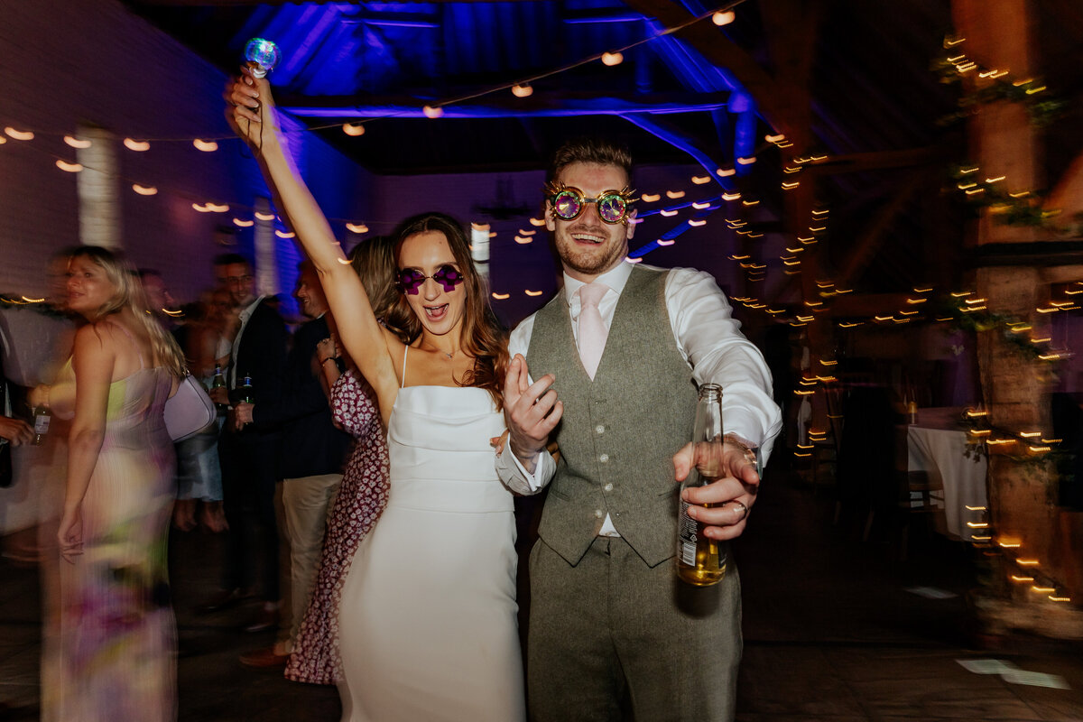 A bride and groom dancing at their wedding reception with sunglasses and goggles on