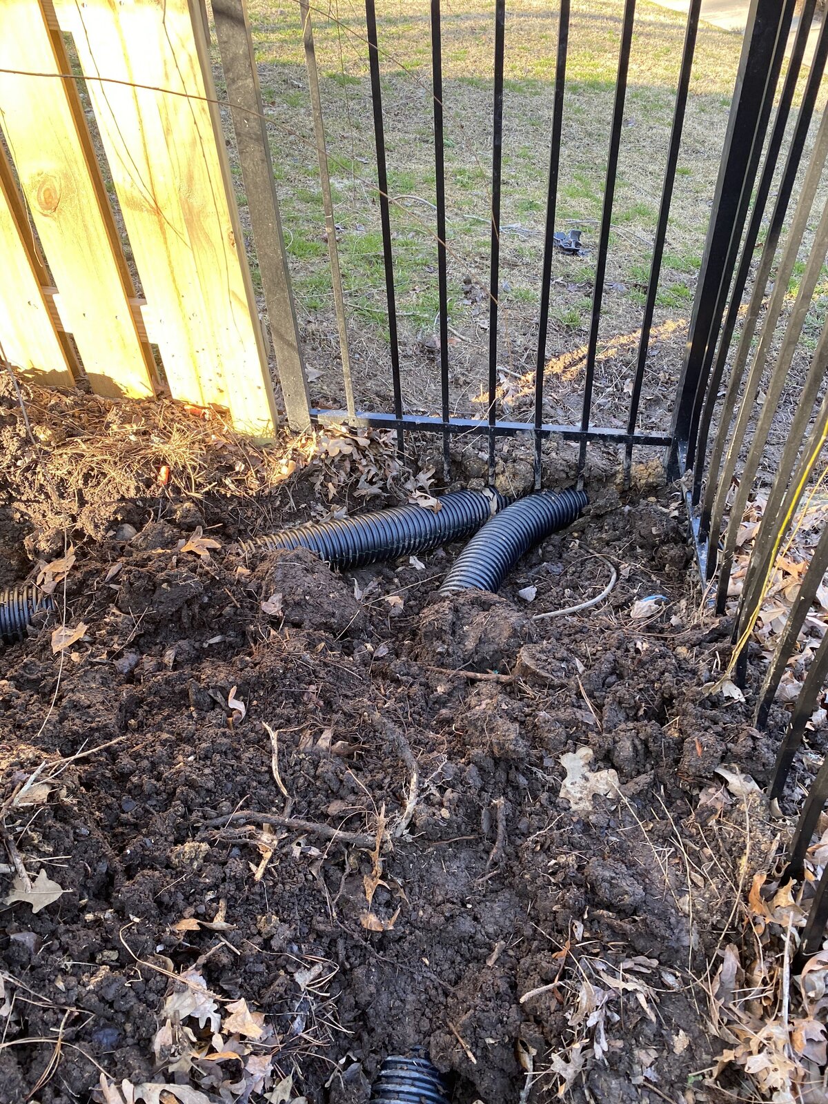 drainage-hoses-going-under-black-metal-fence