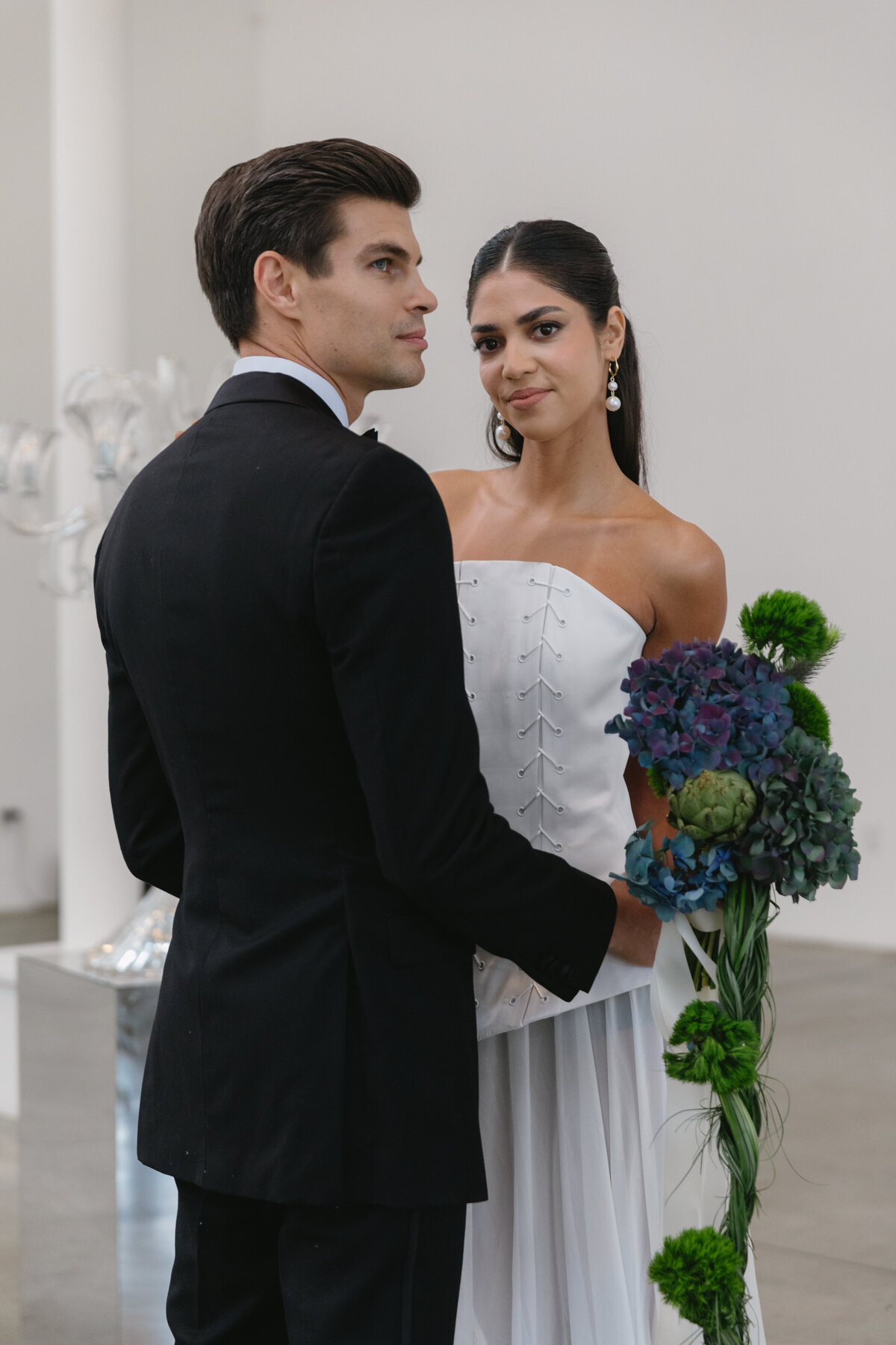 Editorial portrait of a bride and groom embracing, reflected on a mirrored surface inside Sound River Studios in New York City.