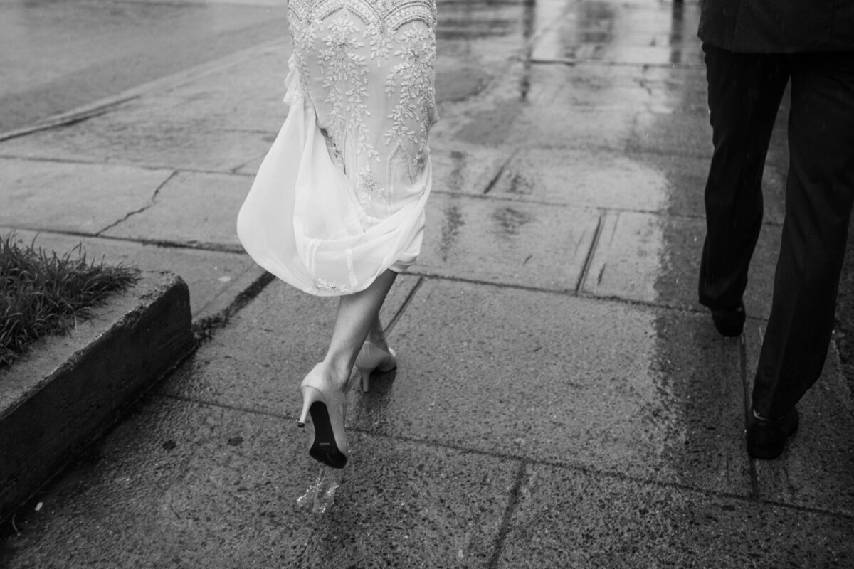 wedding photo of feet of bride and groom walking downtown on a very rainy day in vancouver