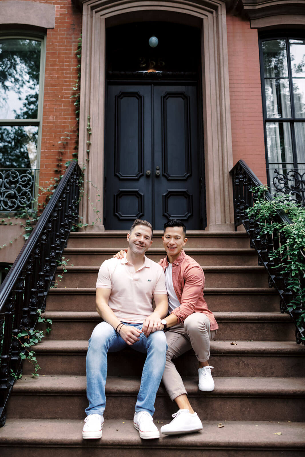 The engaged couple is sitting in an entrance staircase of an ivy-covered building at West Village, NYC. Image by Jenny Fu Studio.