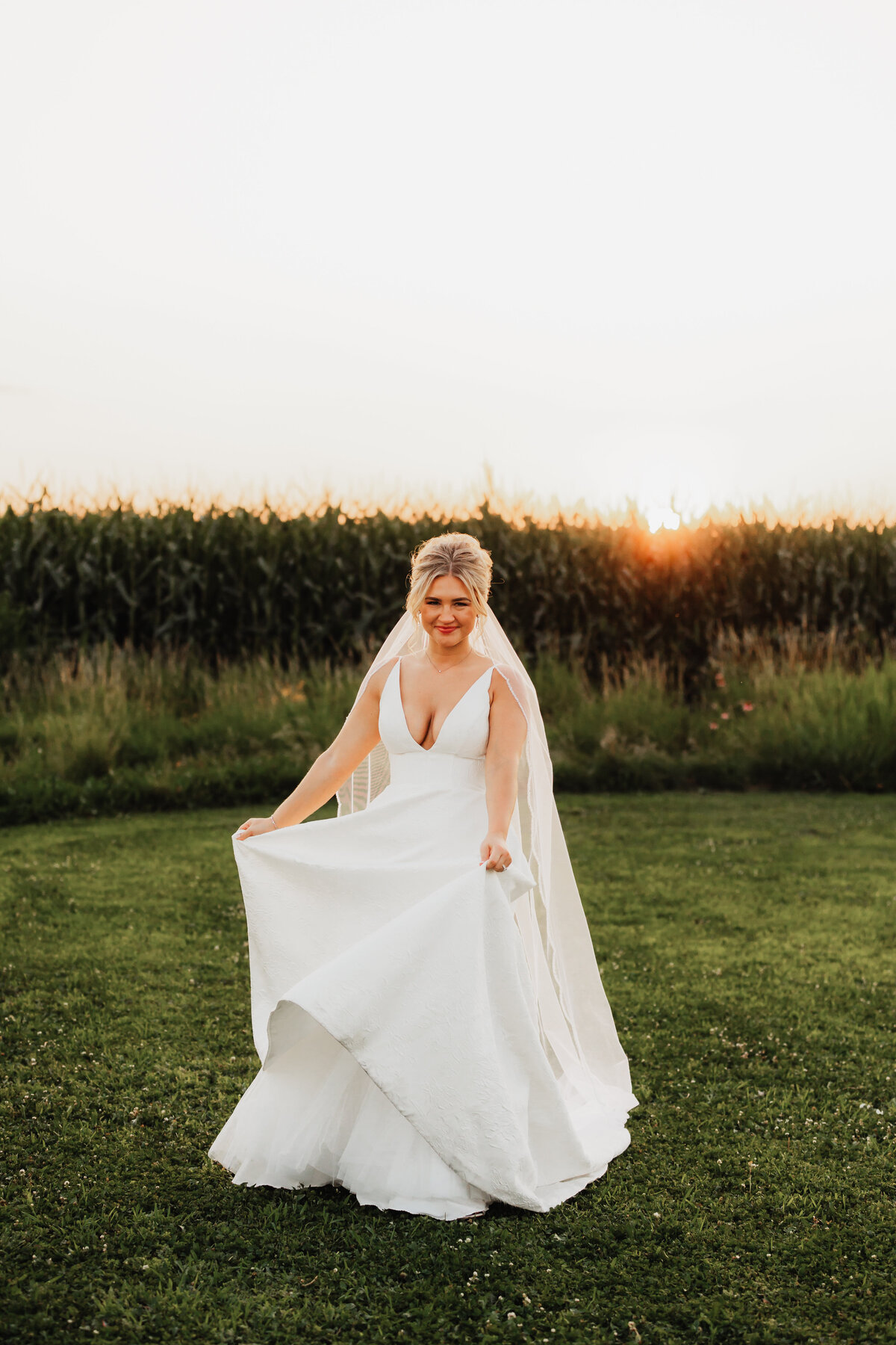 A bride dances in front of a corn field.