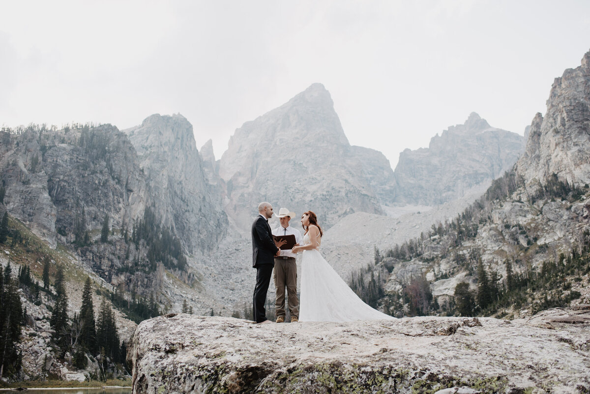 Jackson Hole photographers capture bride and groom holding hands during ceremony
