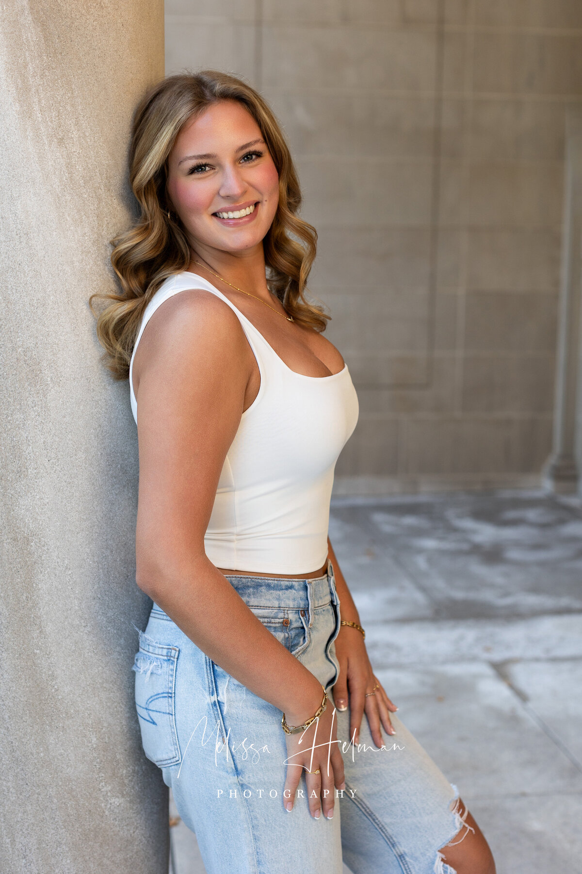 Senior girl smiling leaning up against concrete pillar in Pittsburgh senior session.