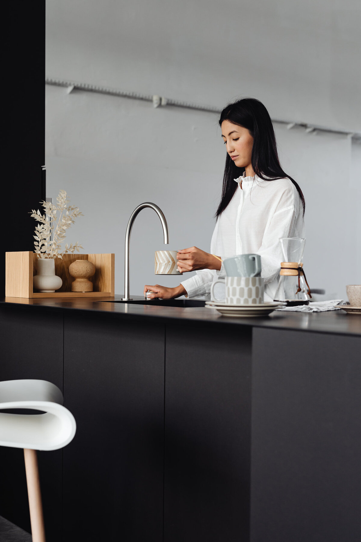 kaboompics_an-adult-young-asian-woman-pours-water-into-a-cup-from-the-tap-in-the-kitchen-22178