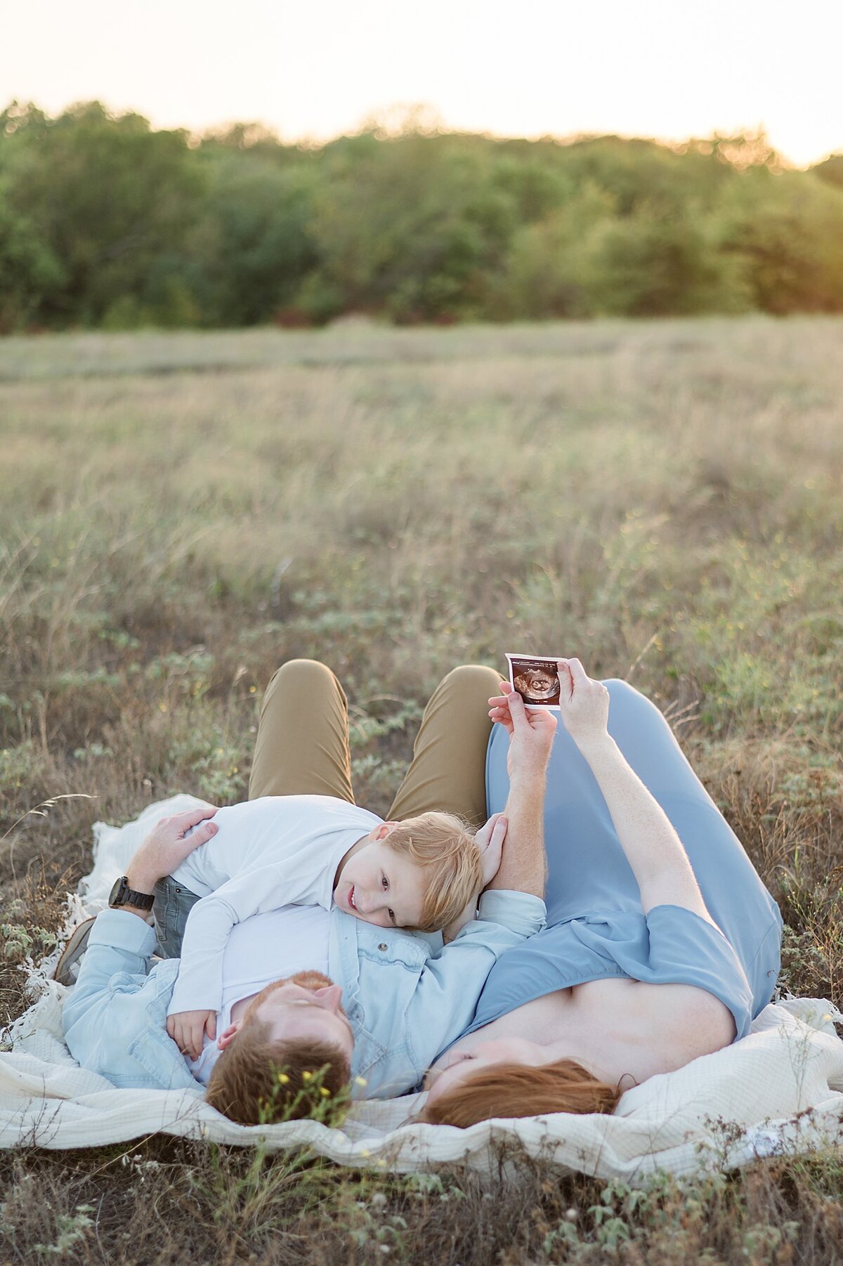 Family cuddling in a field with ultrasound photo