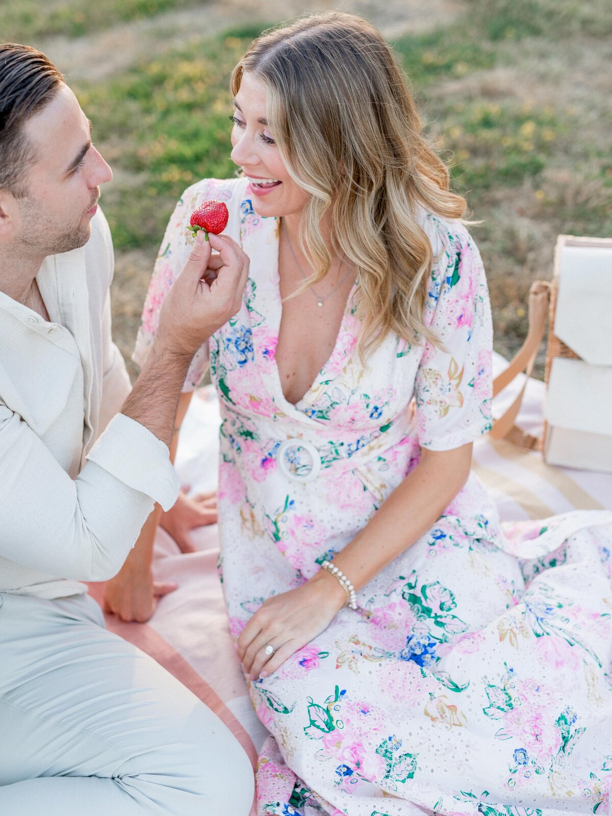 Man feeding strawberry to woman during romantic picnic