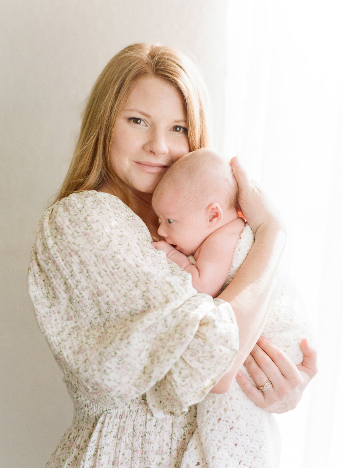 Mom holds her newborn close and looks directly into the camera for a portrait. Image by Raleigh newborn photographer A.J. Dunlap Photography.