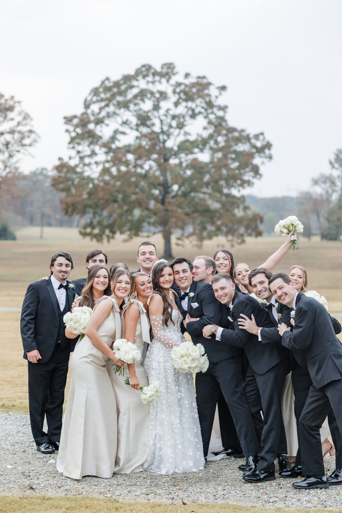 A bride and groom smile surrounded by their extra happy wedding party
