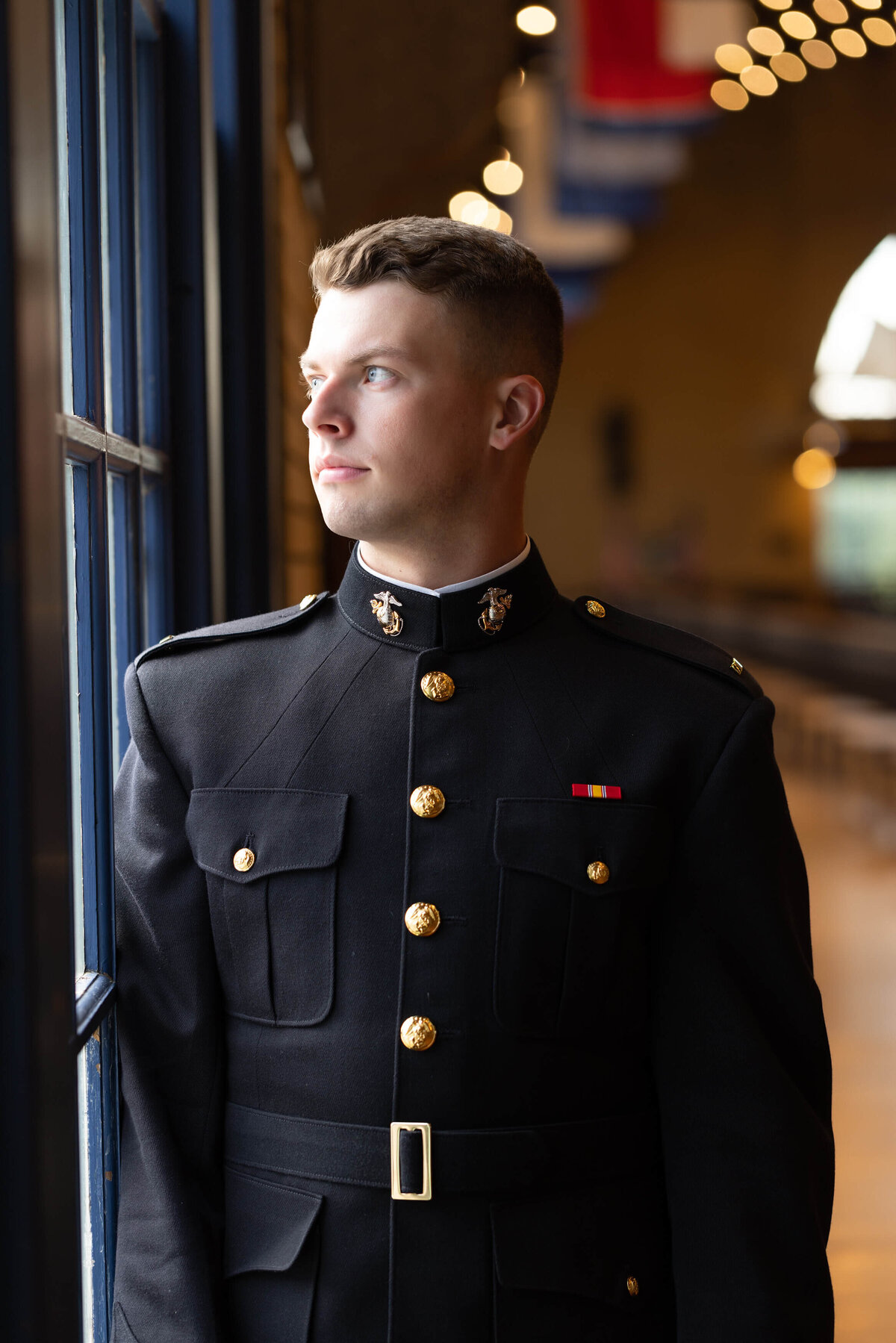 Midshipman Marine poses for a pensive senior photo near the window in Dahlgren Hall at Naval Academy.
