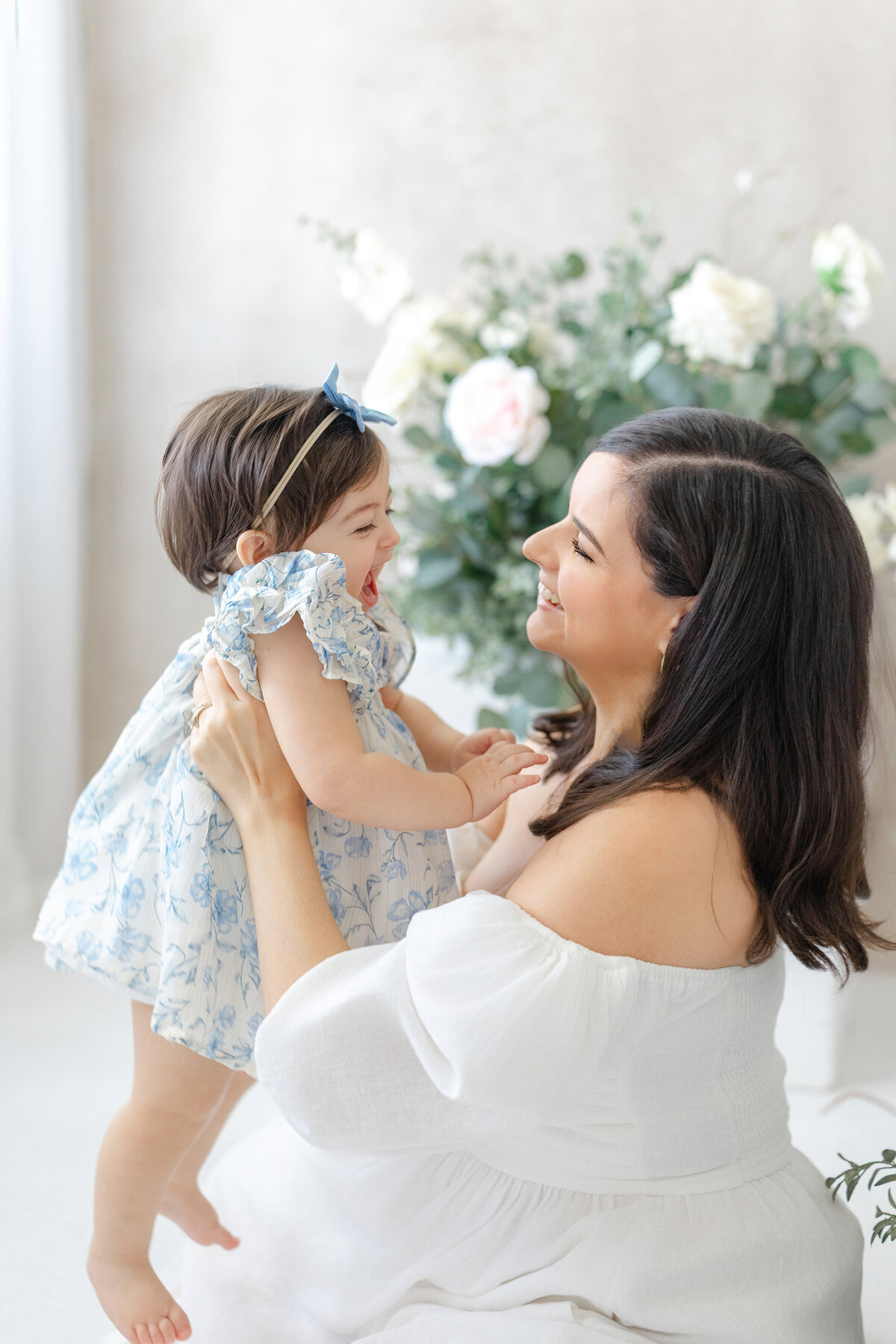 Joyful Tampa motherhood portrait of mom and baby laughing together in soft natural light studio