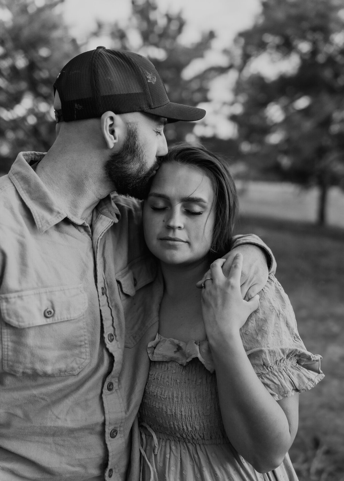 A timeless black-and-white image of a husband and wife quietly, taking a moment to embrace on their families farm during a photo session.