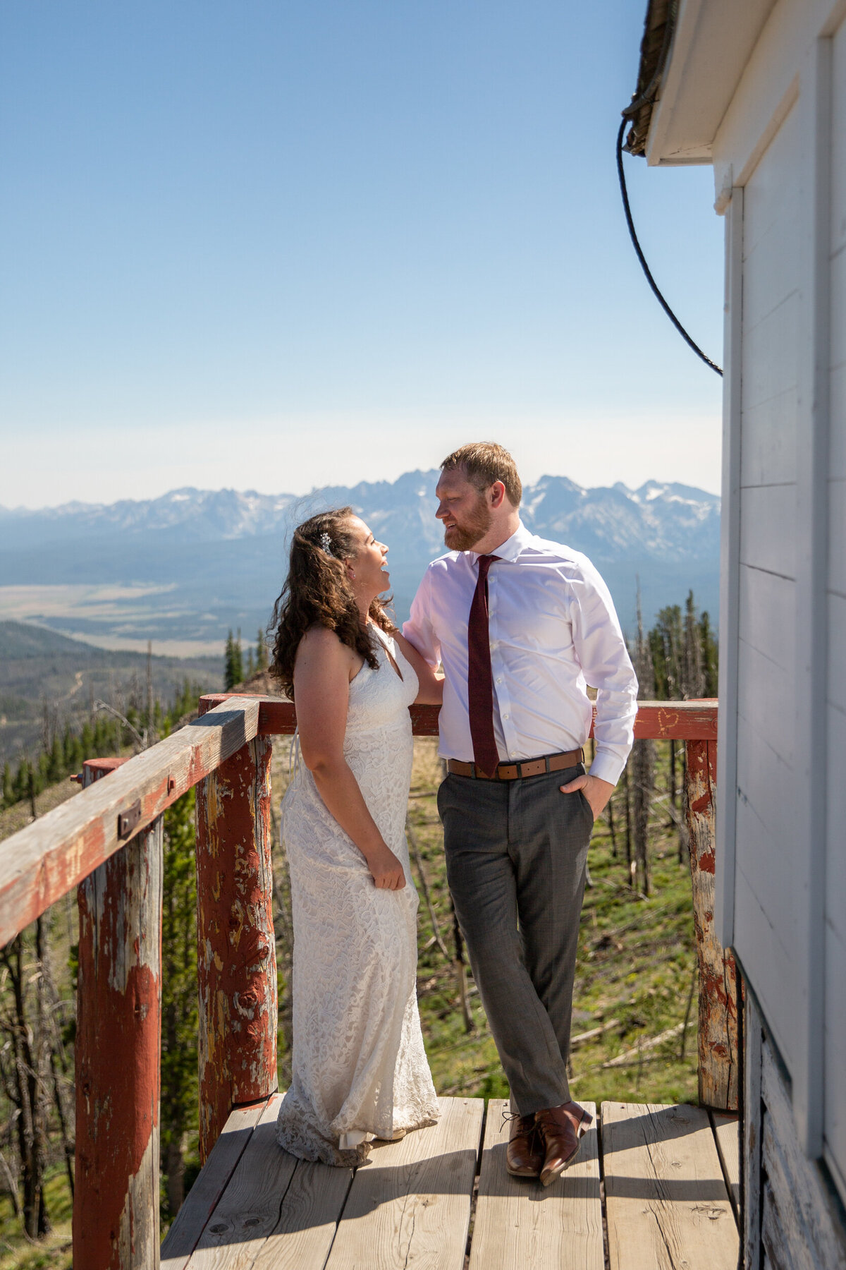 A bride and groom stand on the wooden deck of a fire lookout in Idaho on their wedding day.