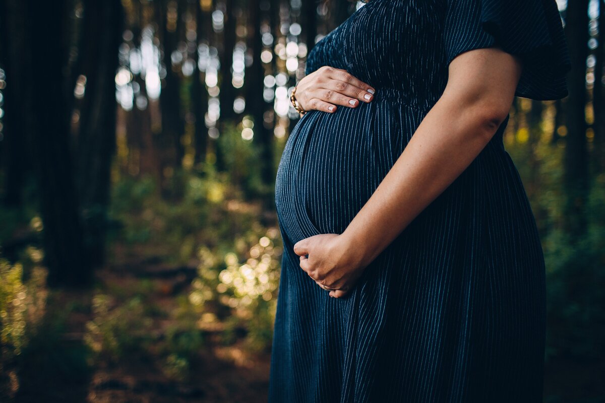 Pregnancy woman standing with hands on her belly.