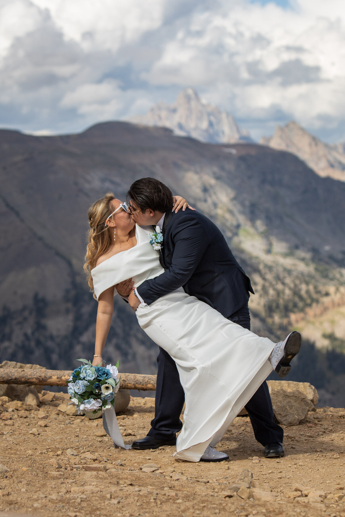 A groom dips his bride as she holds her bouquet in one hand.