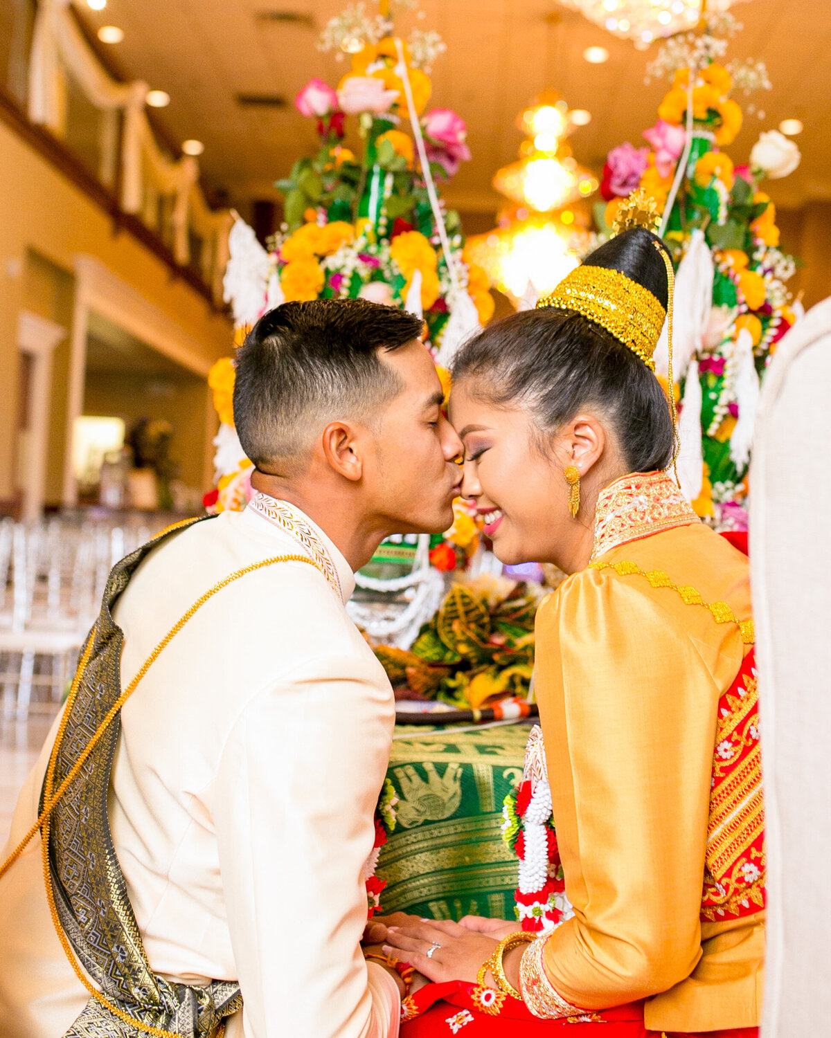 Buddhist groom kisses his bride on the forehead.