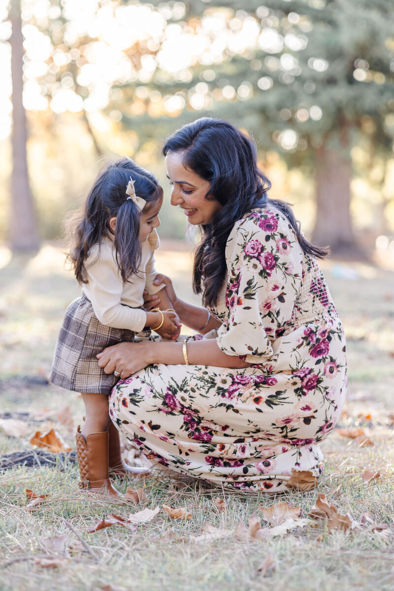 Mom gazing lovingly at toddler daughter during playful moment at fall photoshoot in Milpitas