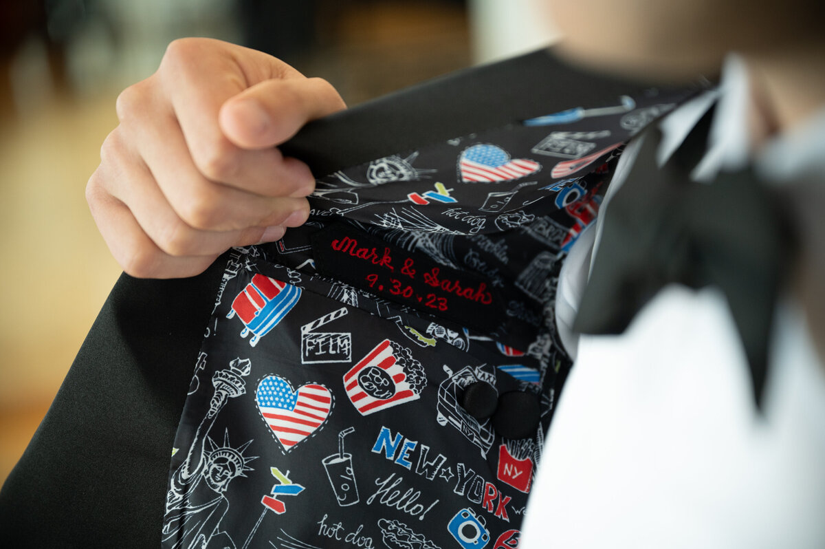 mark shows off the cutom NYC themed lining of his wedding tuxedo
