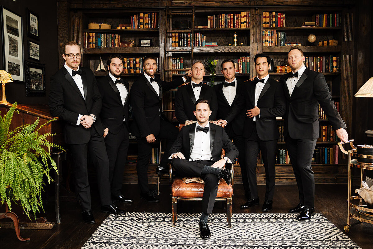 Groom poses with his groomsmen in the library of the Manor House in Littleton Colorado.