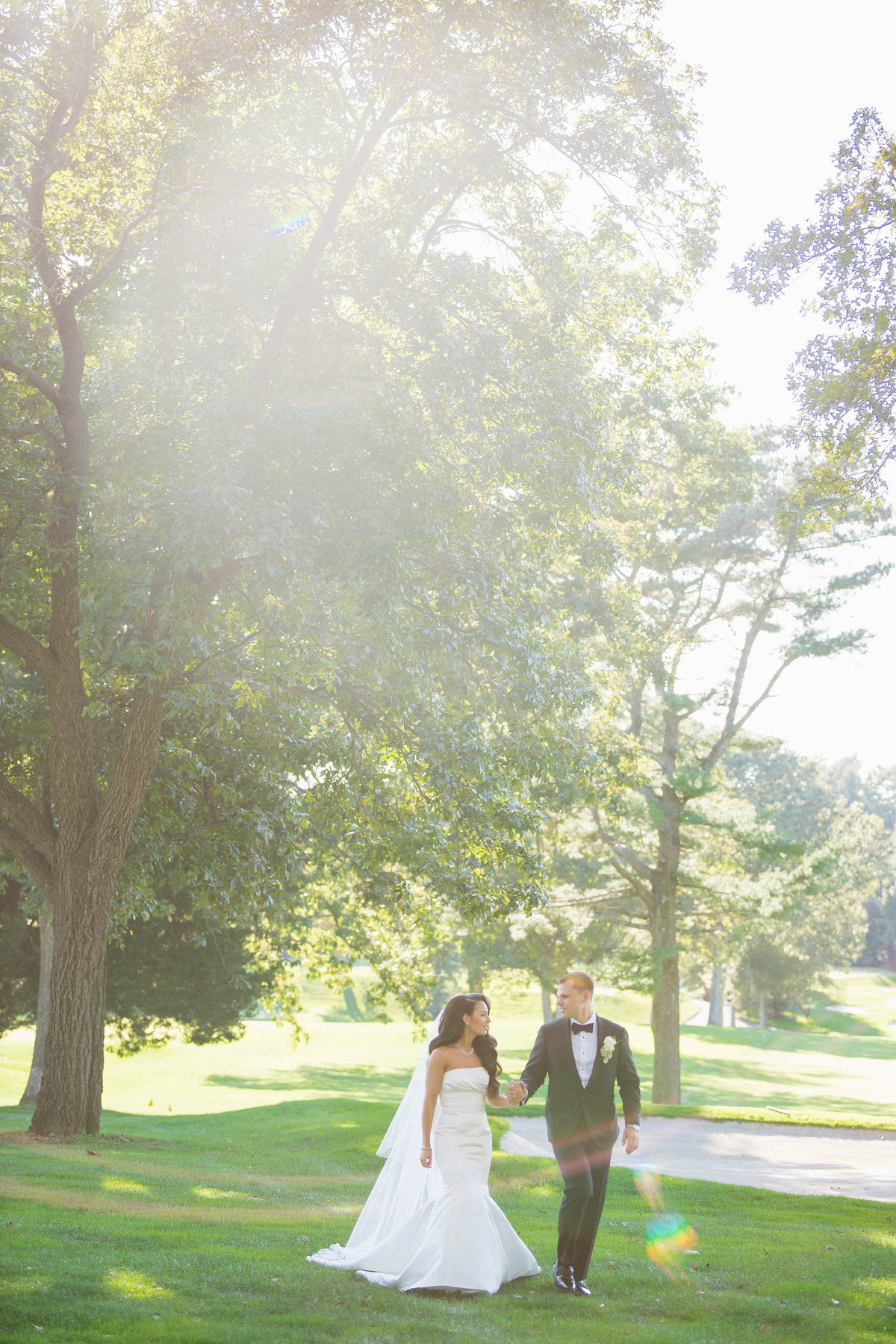 bride and groom holding hands walking on the greens at The Muttontown Club