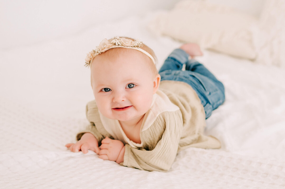 little girl smiling on bed in Springfield MO baby photography studio