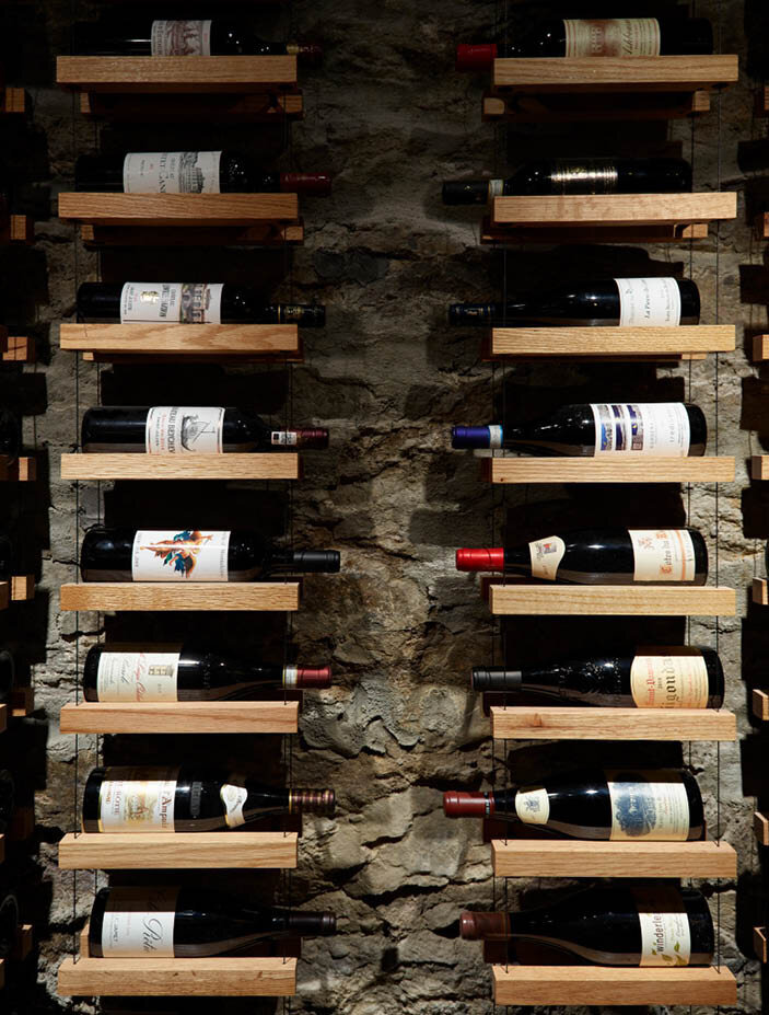 Once a coal cellar, now a modern wine room with original walls, new tile flooring, and air control for ideal wine storage. Designed by Sarah Scales.