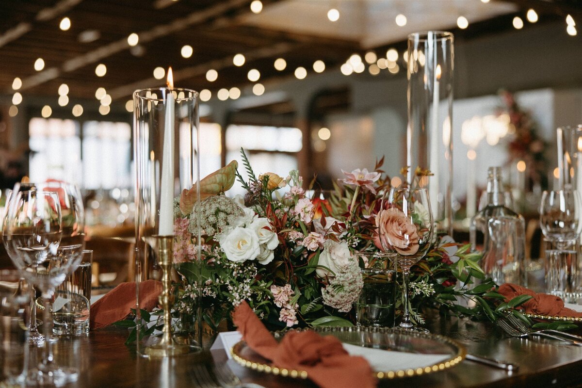 Colorful wedding table decor with burnt orange napkins, crimson,, white and pink florals