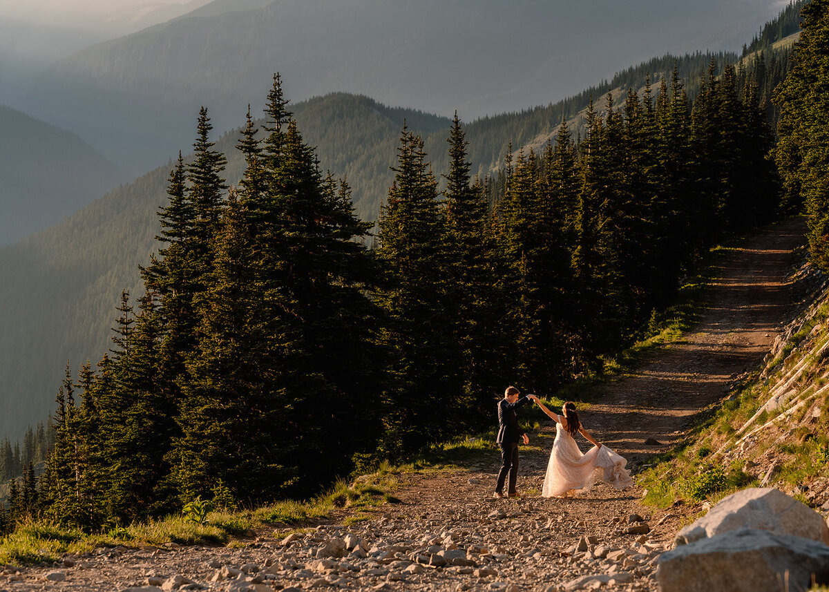 after learning how to elope in Washington State, a couple in wedding attire dances during sunset framed by mountains and trees