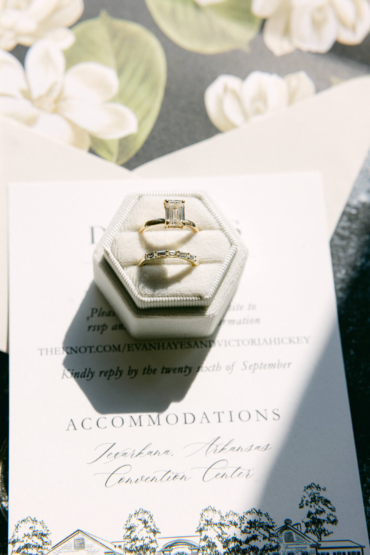 A wedding day photo of the brides rings and wedding invitation below