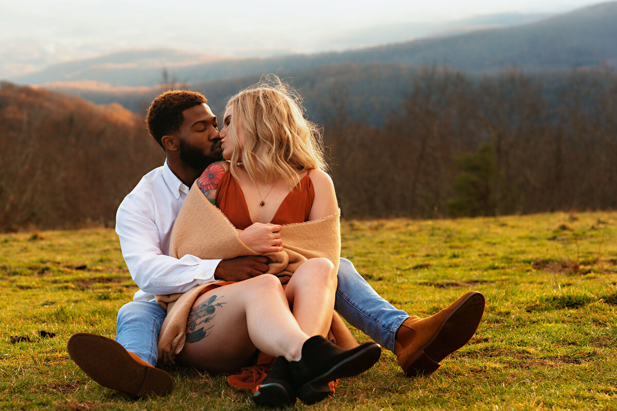 Interracial couple kissing on the grass at Bearwallow Mountain, NC