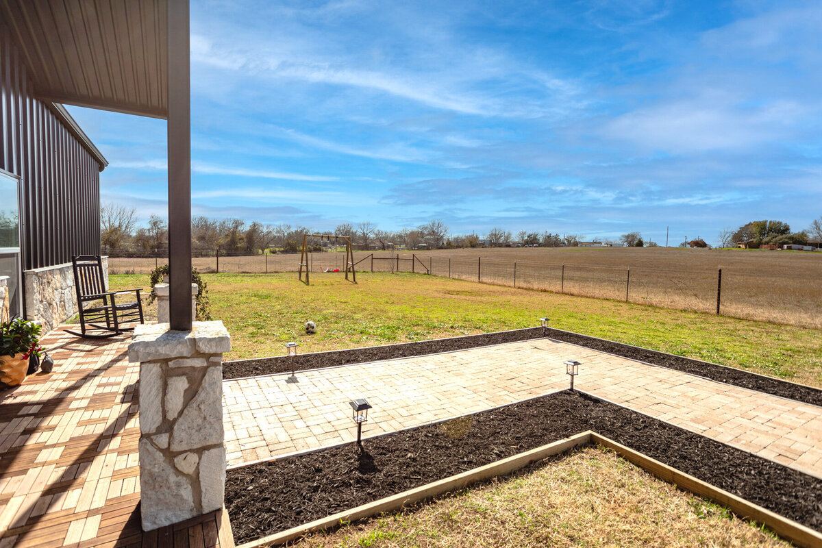Front yard with swing set and beautiful view at this five-bedroom, 3-bathroom vacation rental house for up to 10 guests with free wifi, private parking, outdoor games and seating, and bbq grill on 2 acres of land near Waco, TX.
