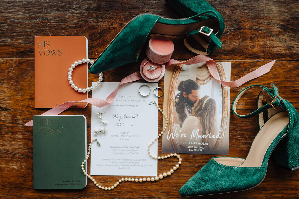 Flatlay of wedding details including invitations, jewelry anf shoes