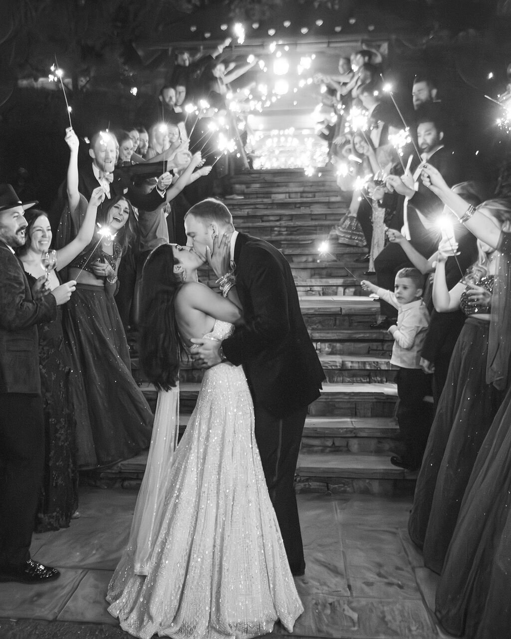 Black and white sparkler exit moment with the couple kissing at the bottom of the staircase at Old Edwards Inn.
