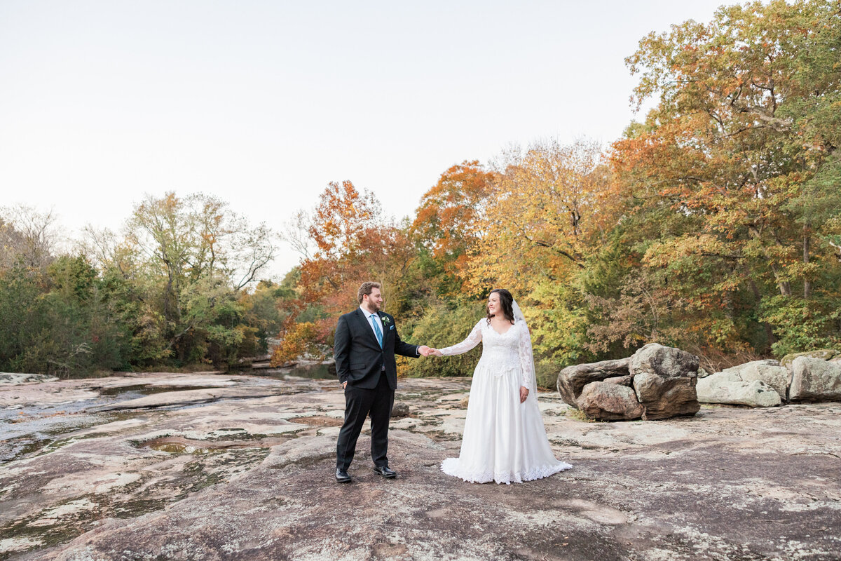 A wedding couple reaching their hands out to hold each other and smiling