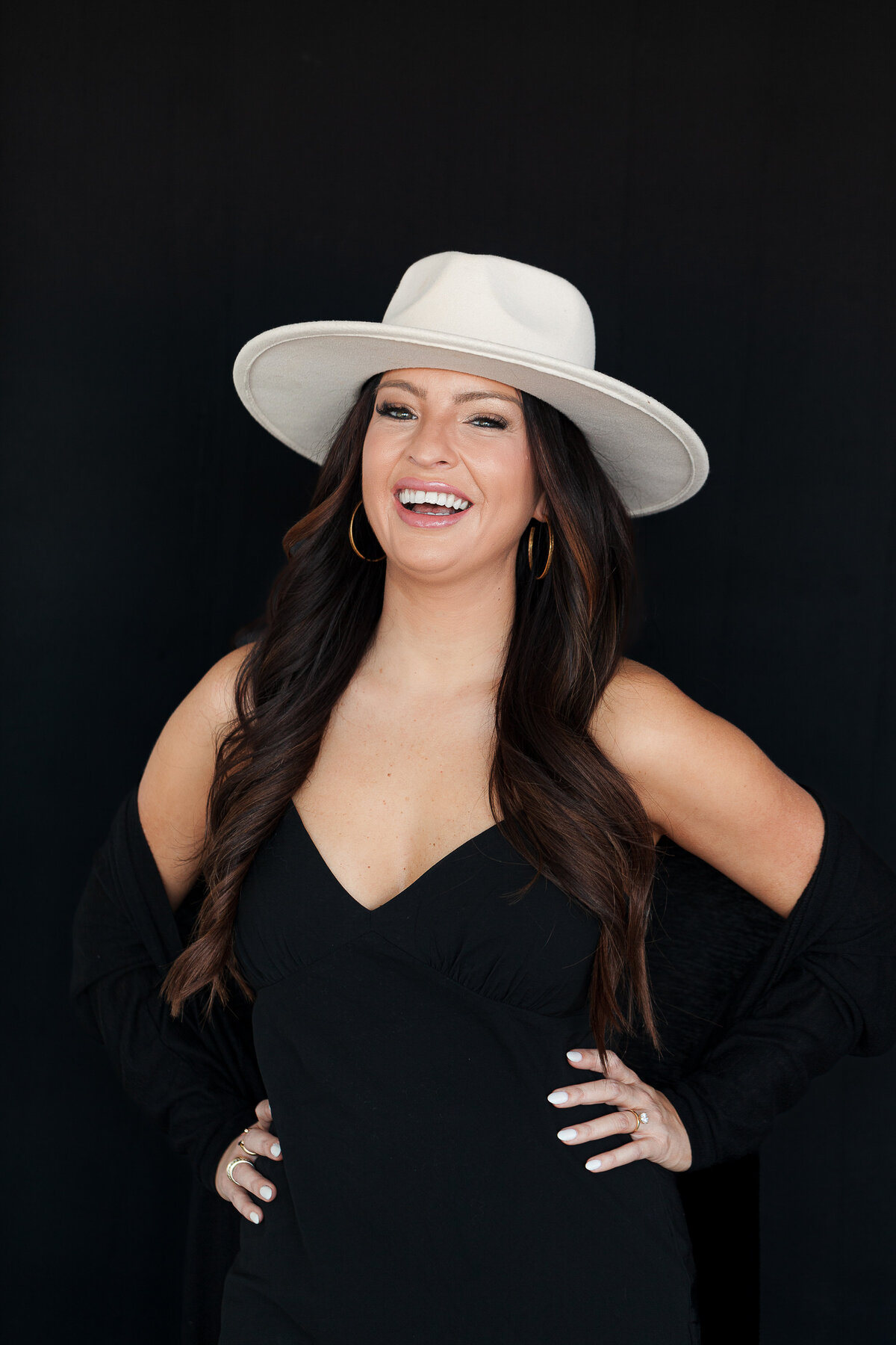 confident-woman-power-pose-portrait-black-dress-black-background-hat-for-brand-session-charlotte