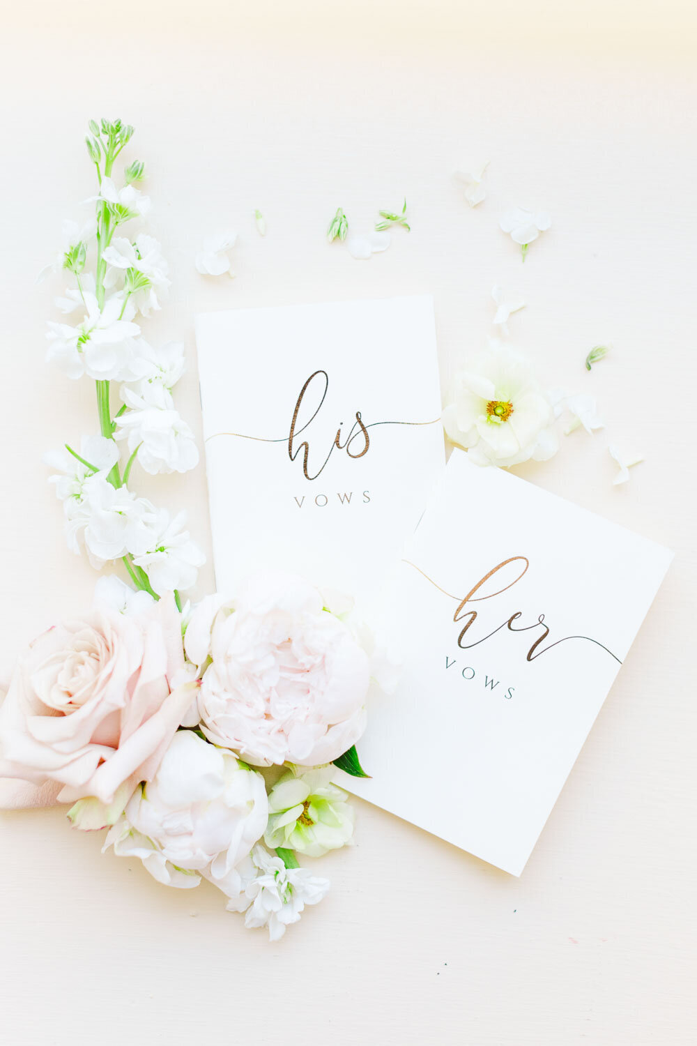 His and her vow books with flowers