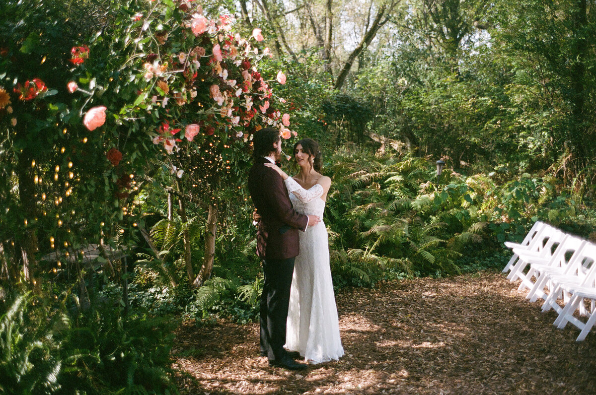bride and groom dancing by flowers and greenery 