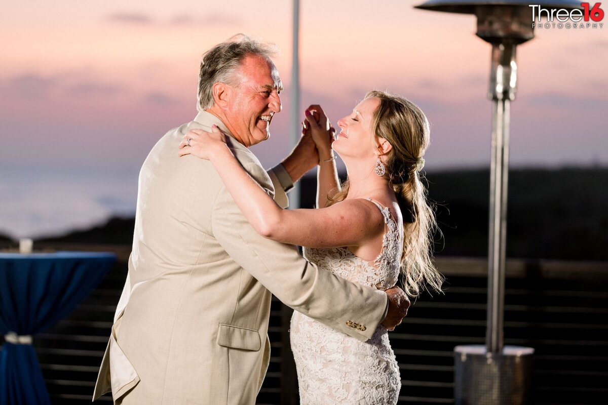 Bride dances with her father during her wedding reception as the sun sets on the venue