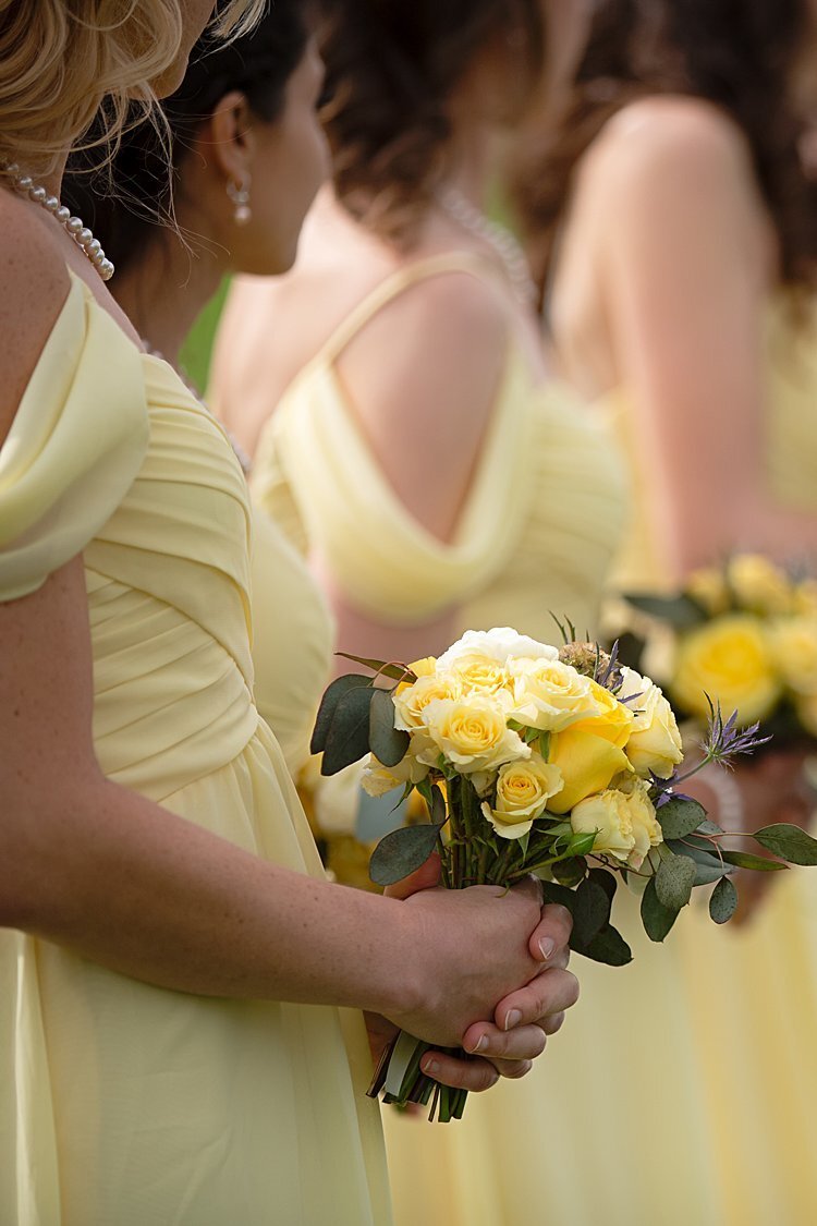 Bridesmaids in yellow hold yellow floral bouquets during wedding ceremony