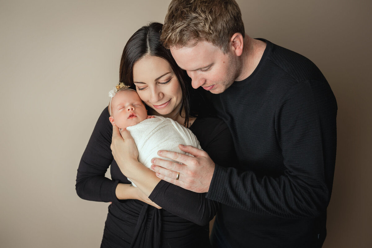 new parents looking down at their newborn baby girl at Hamilton, ON newborn photography studio