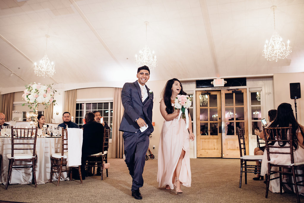 Wedding Photograph Of Groomsman And Bridesmaid Carrying a Bouquet While Walking Los Angeles