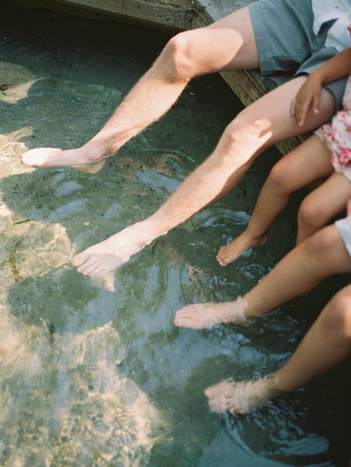 Three sets of feet dip in a fountain.