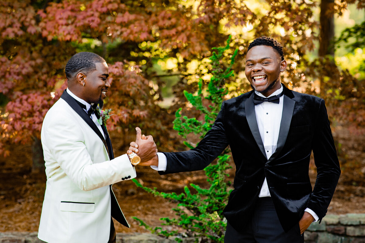 Groomsman greeting groom during photos, laughing together