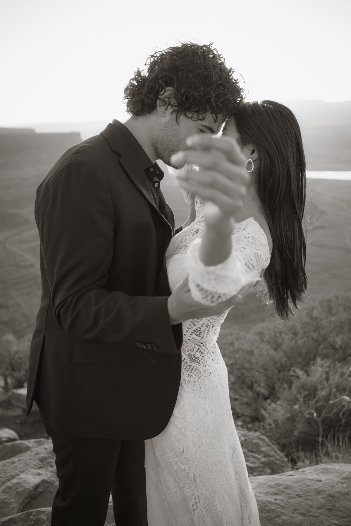 Black and white portrait of bride and groom in Moab at sunrise playing with depth of field
