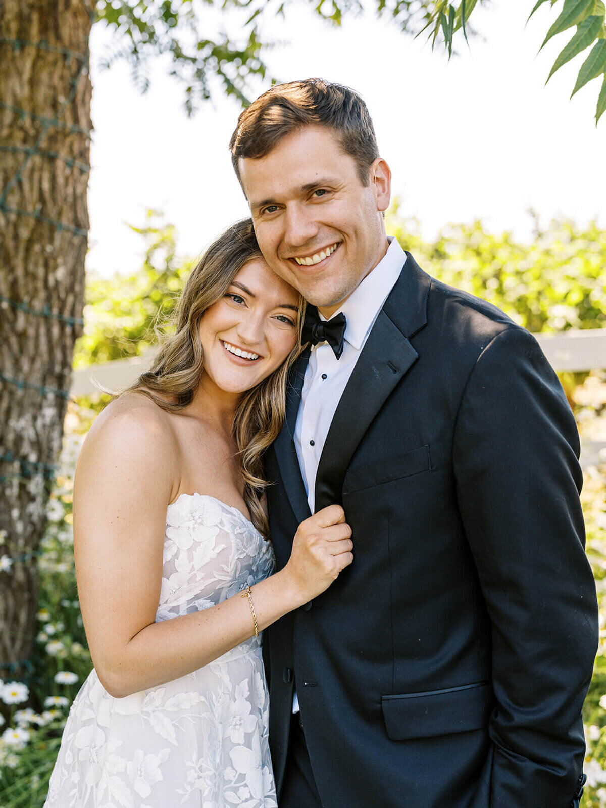 A bride and groom embracing and smiling at the camera.