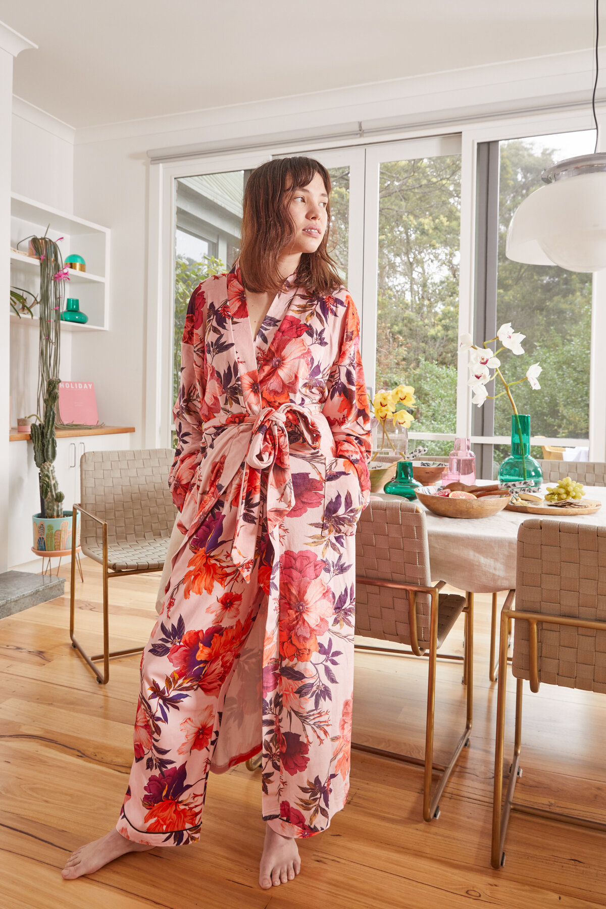 Model wearing floral robe in modern Melbourne dining room with styled dining table and glass vases