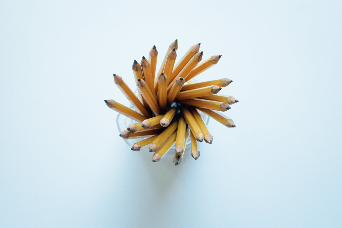brand photographer takes a stock image photograph of a top down view of yellow pencils in a cup against a white background