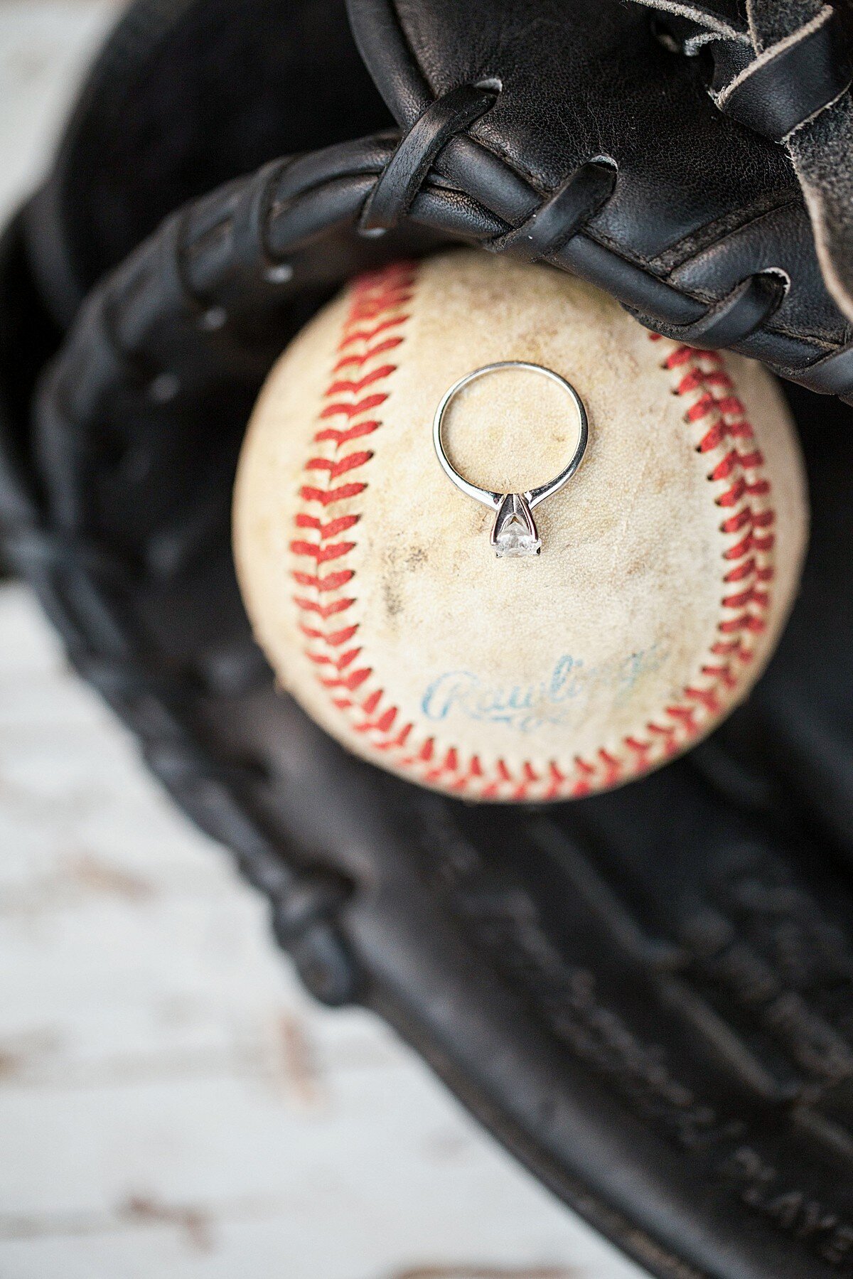 Engagement ring resting on baseball in glove