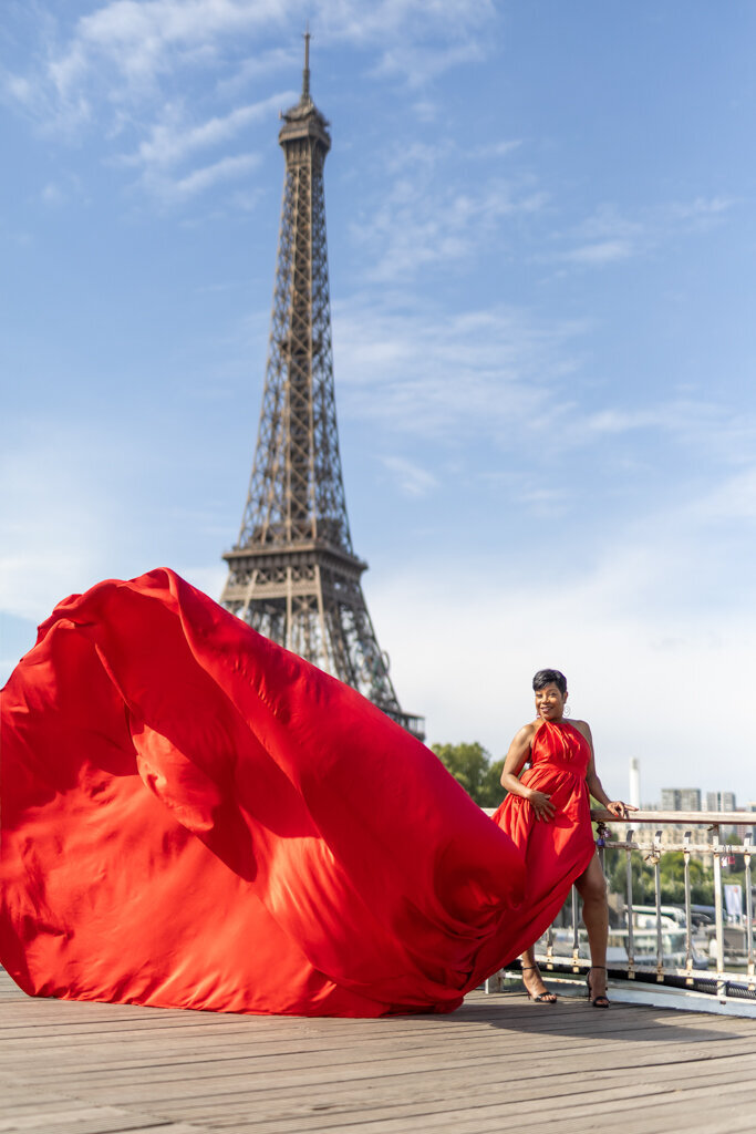 Flying dress portrait on Paris bridge with flowing red gown and Eiffel Tower view